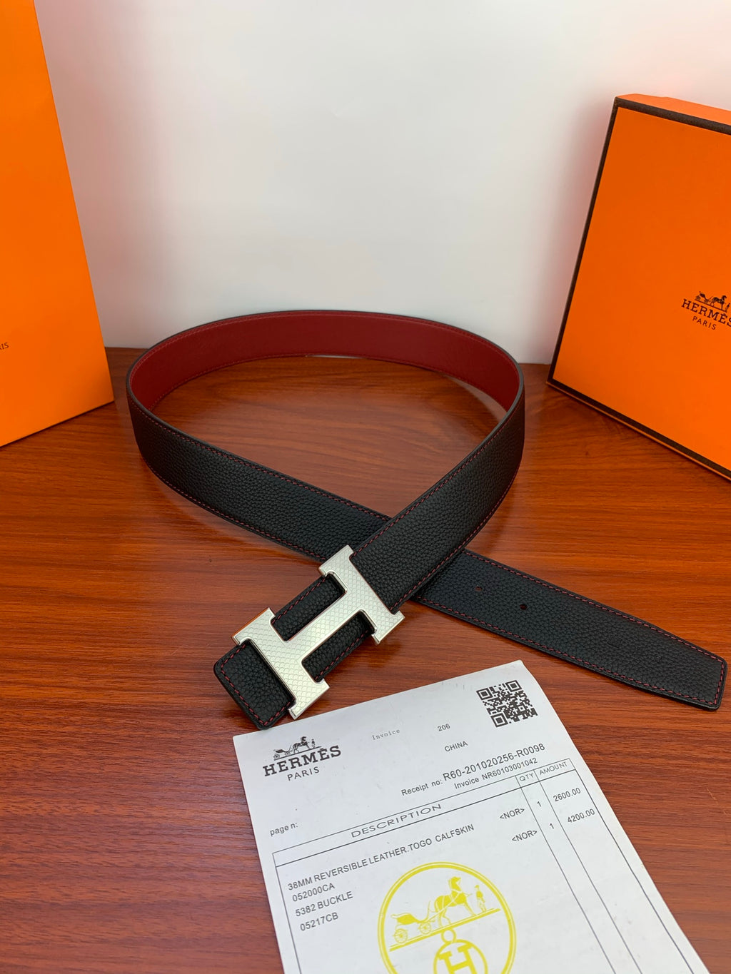 Reversible leather belt laid flat with silver-tone H buckle and dark strap