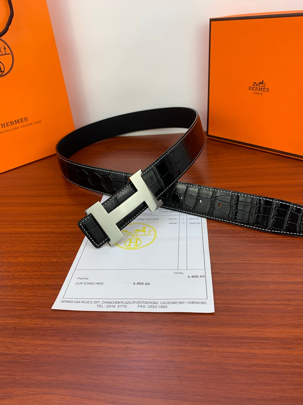 Dark croc-embossed leather belt with gold-tone buckle, laying flat.
