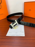 Dark croc-embossed leather belt with gold-tone buckle, laying flat.