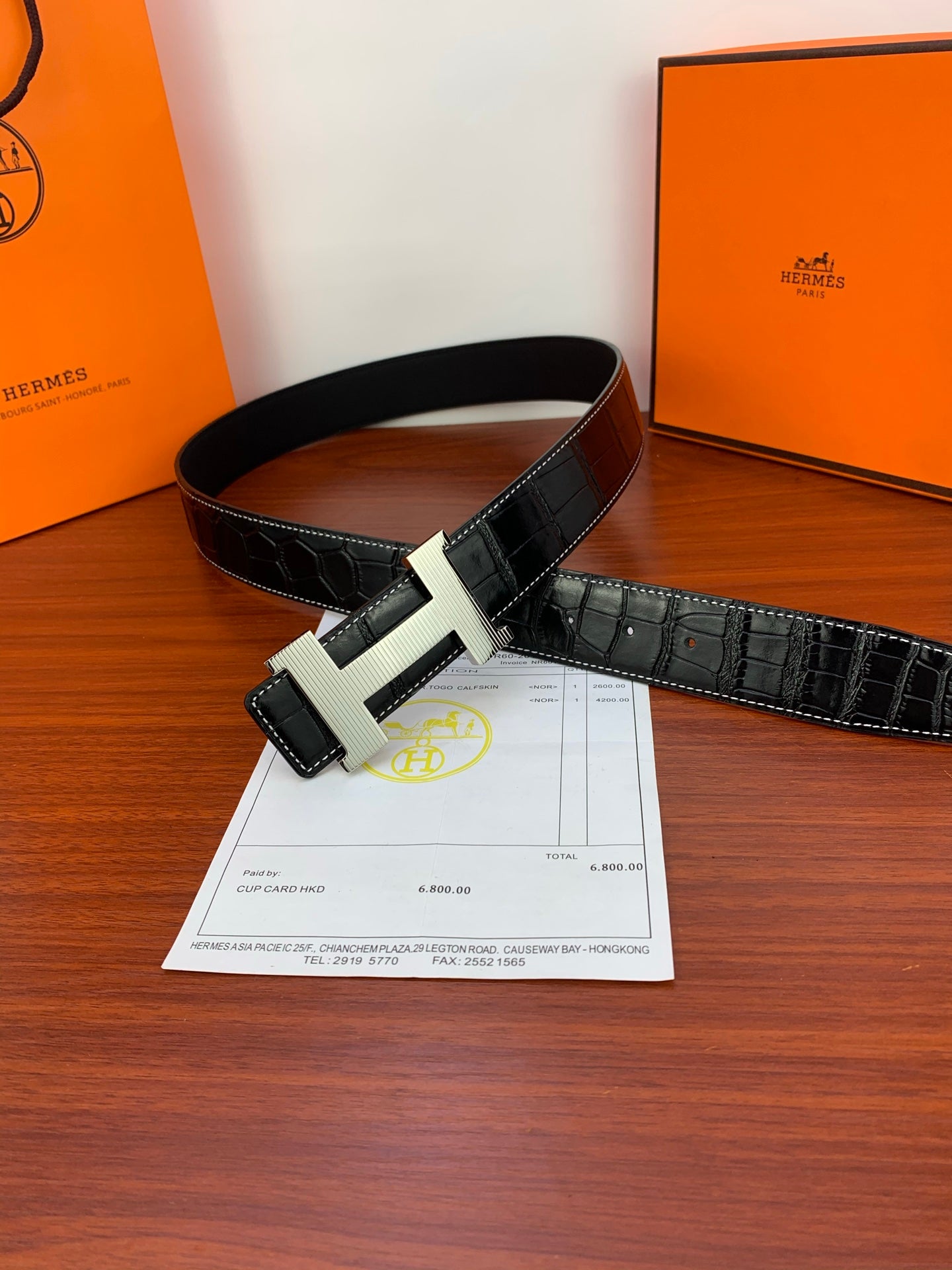 Dark croc-embossed leather belt with gold-tone buckle, laying flat.