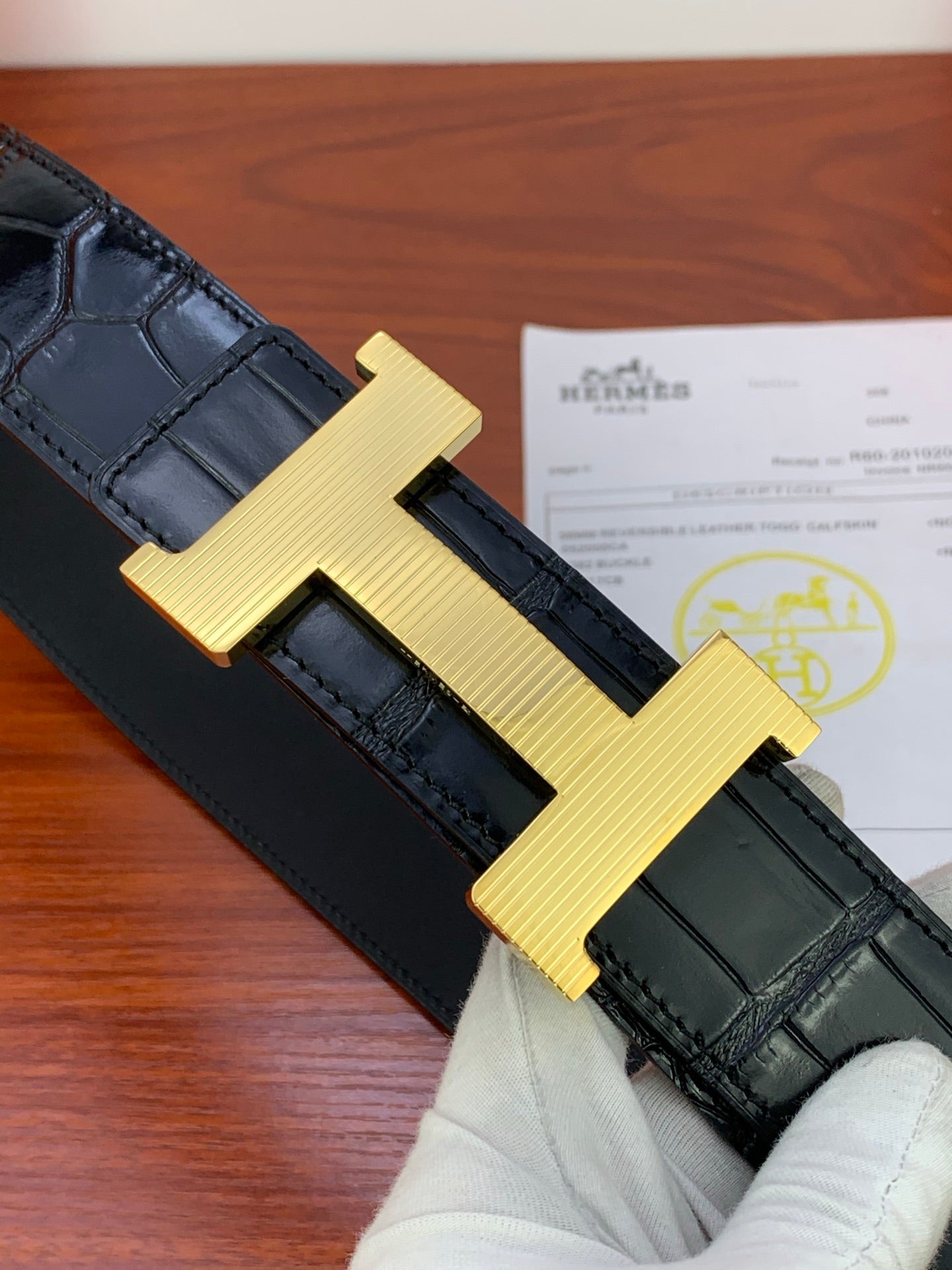 Hermes belt close-up: gold-tone H buckle on dark textured leather strap