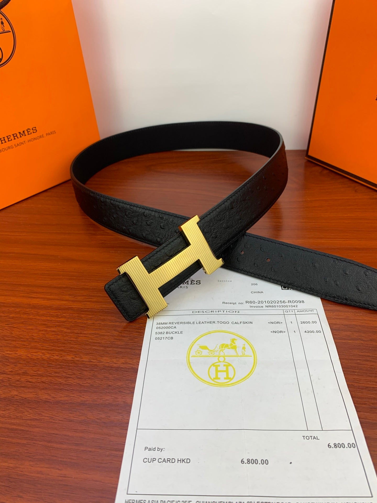 Black leather belt with gold H buckle on top of paperwork
