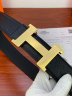 Black leather belt with textured grain and gold H buckle, close-up view