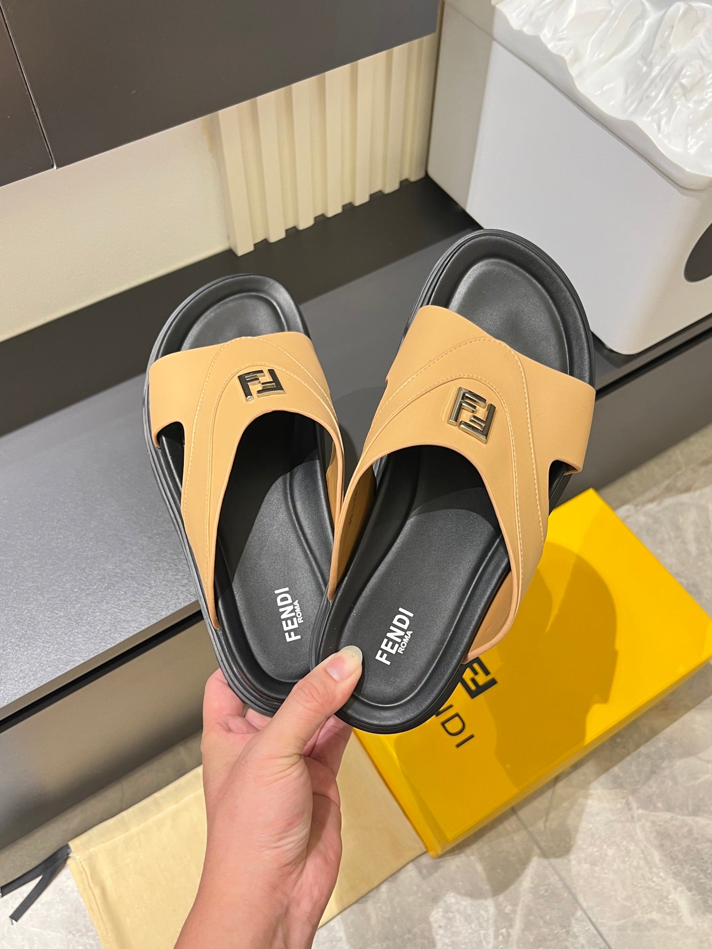 Tan Fendi slide sandals with black footbed and logo strap, shown side view.