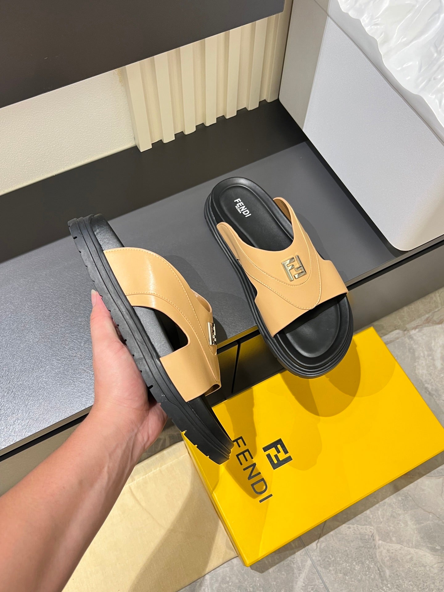 Tan Fendi slide sandals with black sole tread and logo strap, side view.