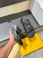 Fendi black slide sandals held beside yellow box, thick rubber sole