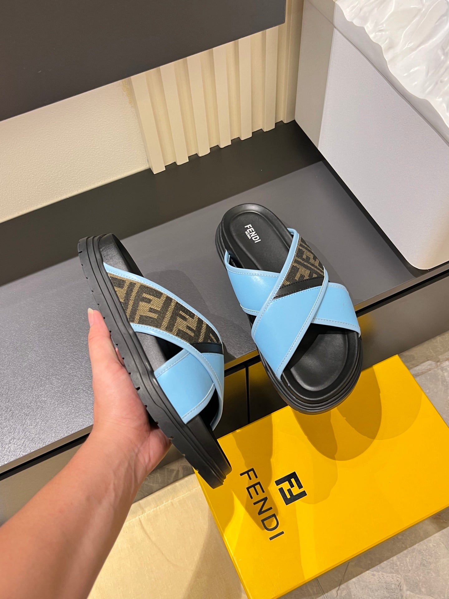 Fendi slide sandals with light blue straps and FF monogram panel; angled view of soles
