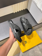Fendi black slide sandals held in hand, thick sole and crossed upper straps