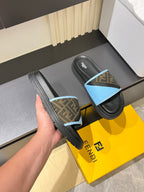 Fendi slide sandals held in hand; black sole with light blue FF strap