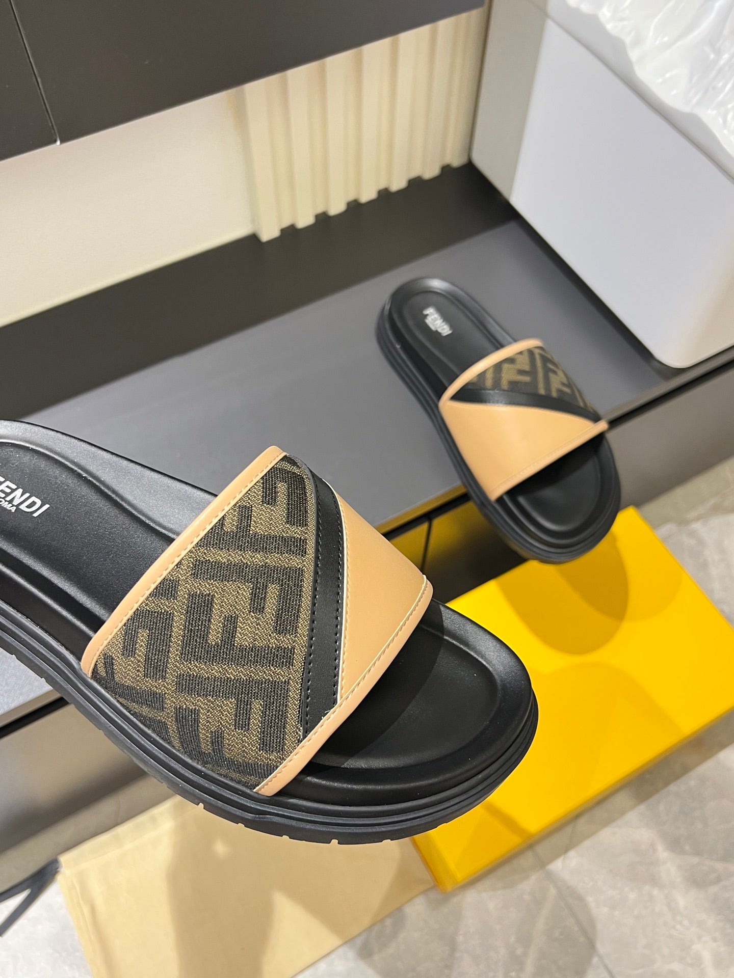Fendi slide sandals, close view of tan FF logo strap on black thick sole