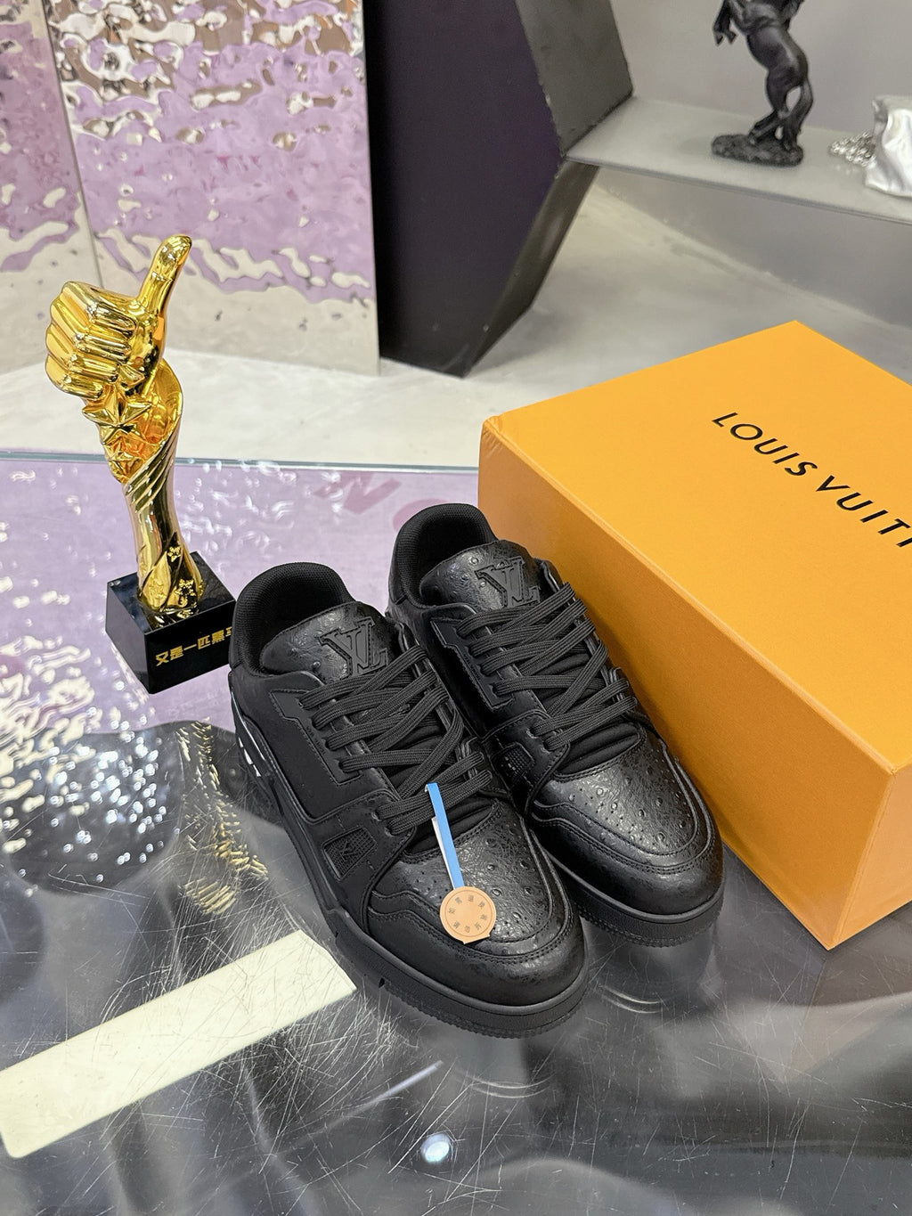 Black lace-up sneakers featuring textured uppers and round gum-style emblem on tongue