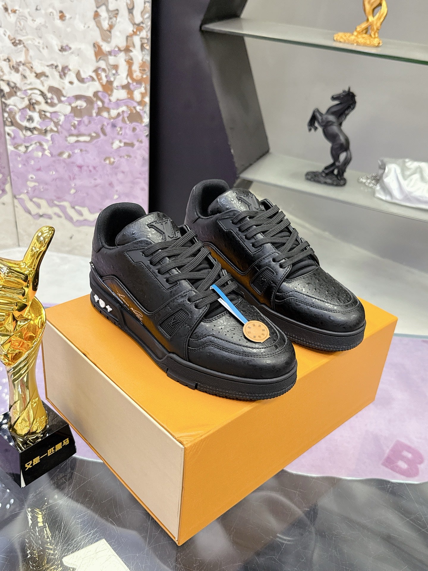 Pair of black lace-up sneakers on a box with textured uppers and rubber outsoles