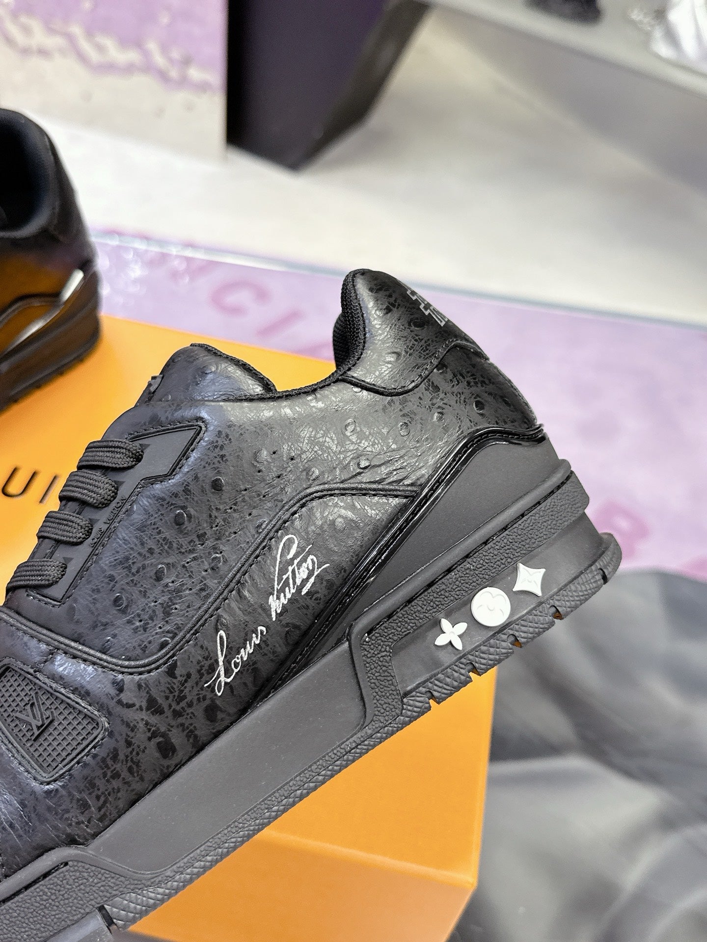 Black low-top sneaker close-up with lace-up front, signature-style side logo, and strap