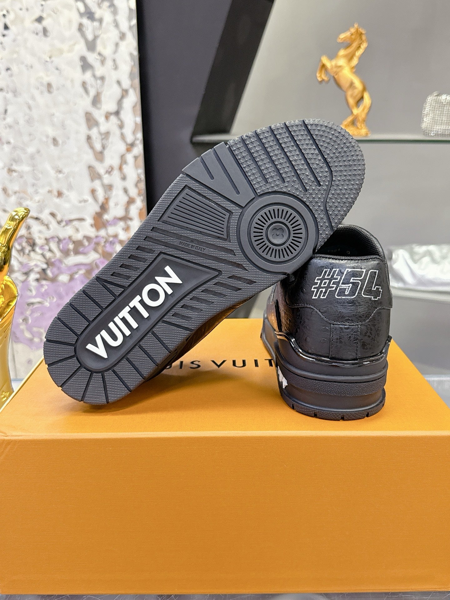 Black sneaker outsole with tread pattern and embossed "VUITTON" logo on rubber sole