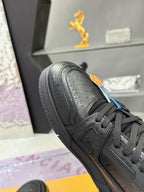 Black sneaker close-up with lace-up eyelets, embossed logo on side, and textured toe