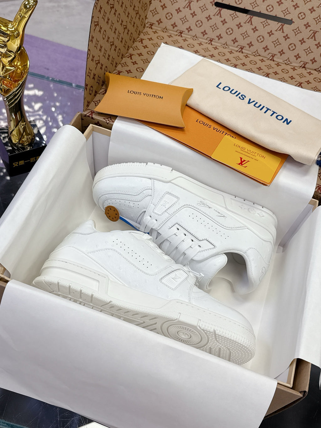 Louis Vuitton white low-top sneakers in a shoe box, with textured sole and lace uppers