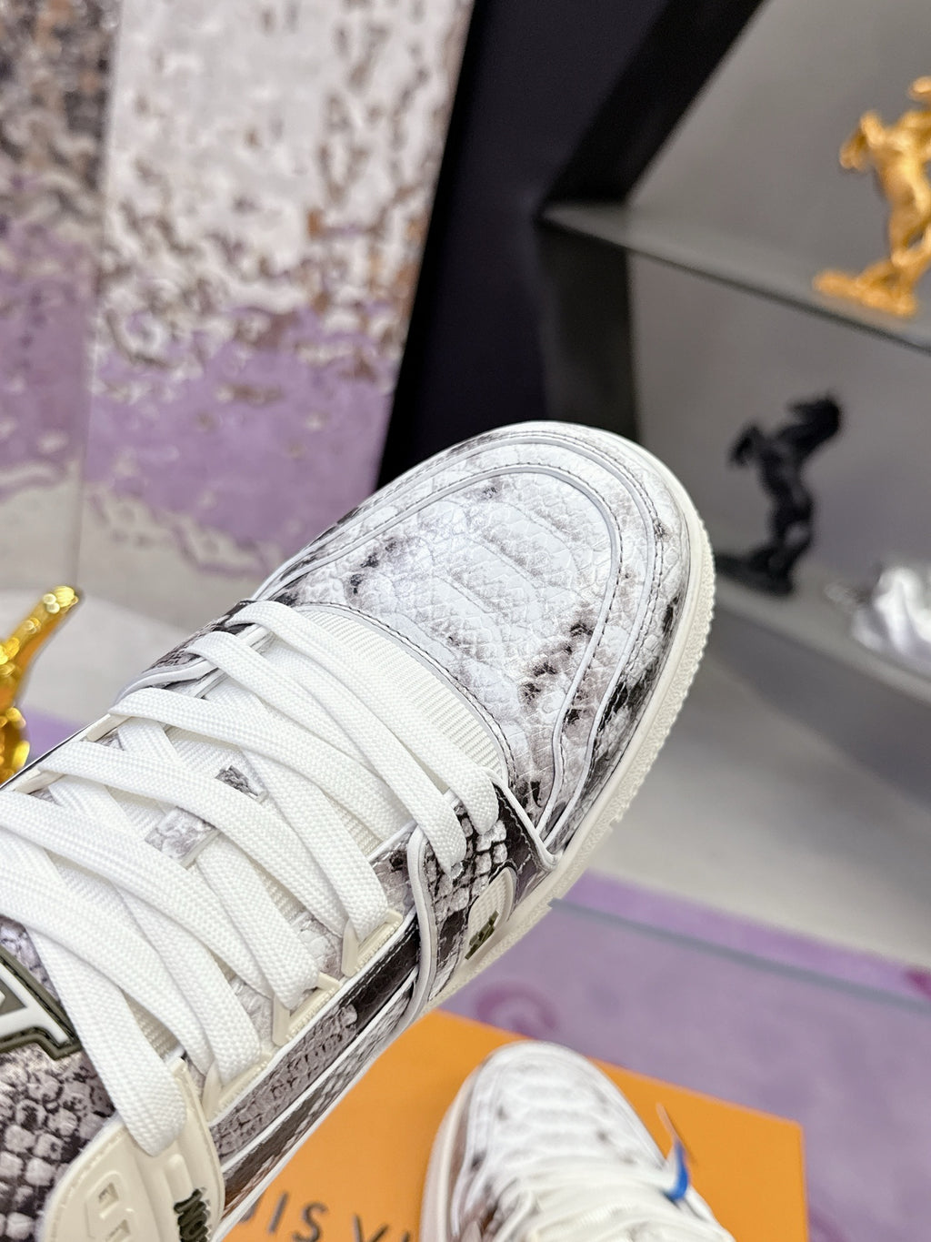 Close-up of white Louis Vuitton sneaker with woven texture, white laces, and logo patch