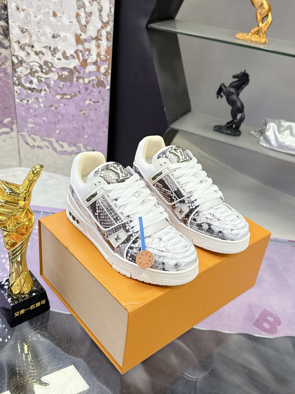 Pair of white Louis Vuitton sneakers with black logo print and patterned uppers
