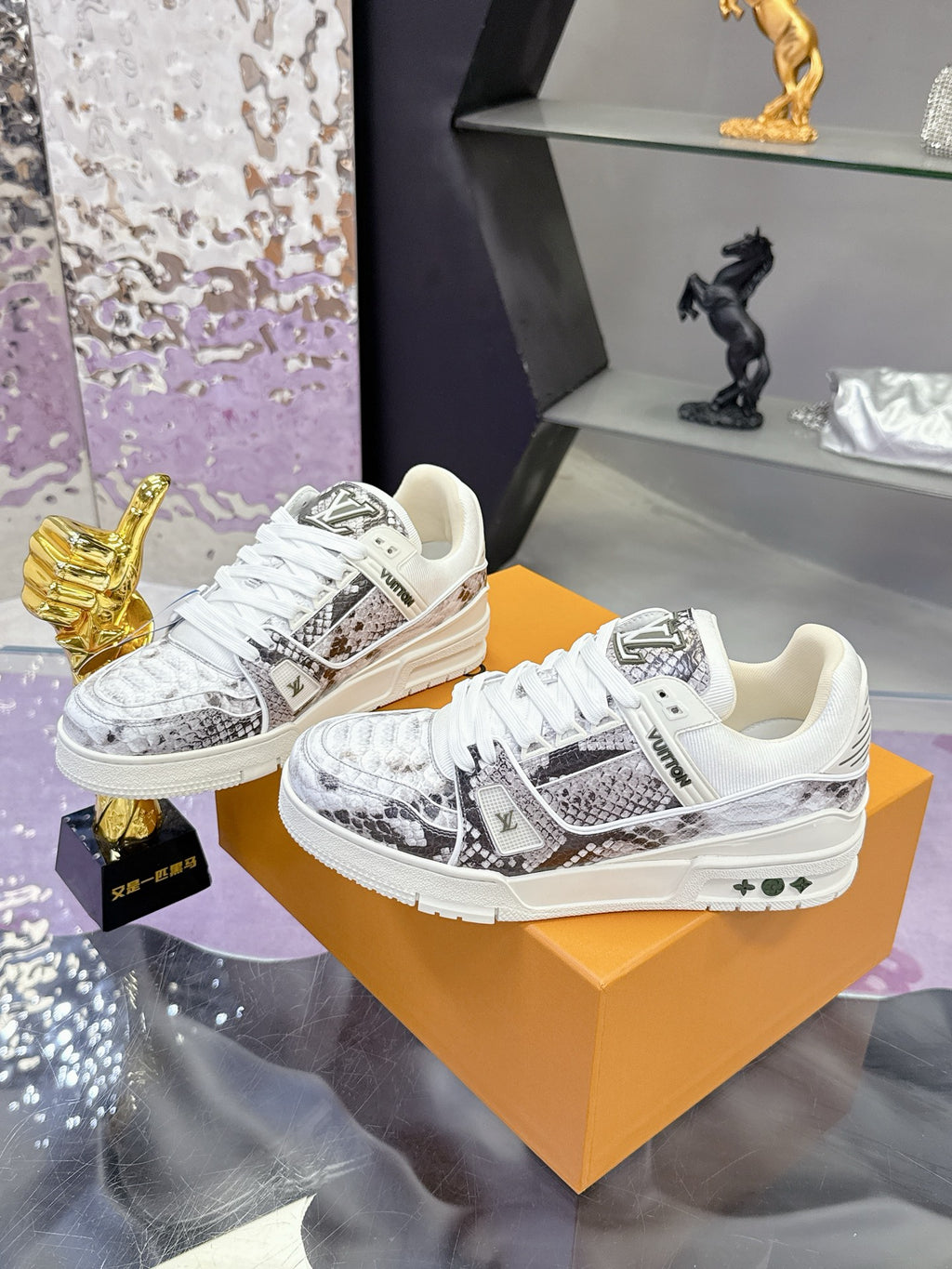 White Louis Vuitton low-top sneakers on orange box, with logo patch and white laces