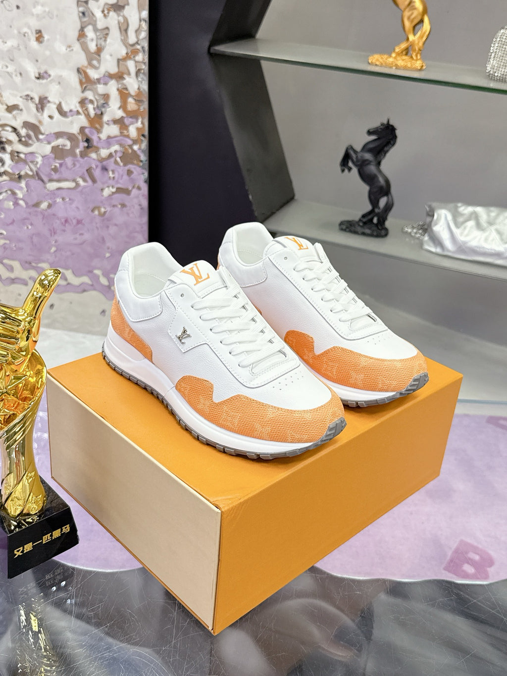 White lace-up sneakers with orange side panels and stitched logo patch on tongue
