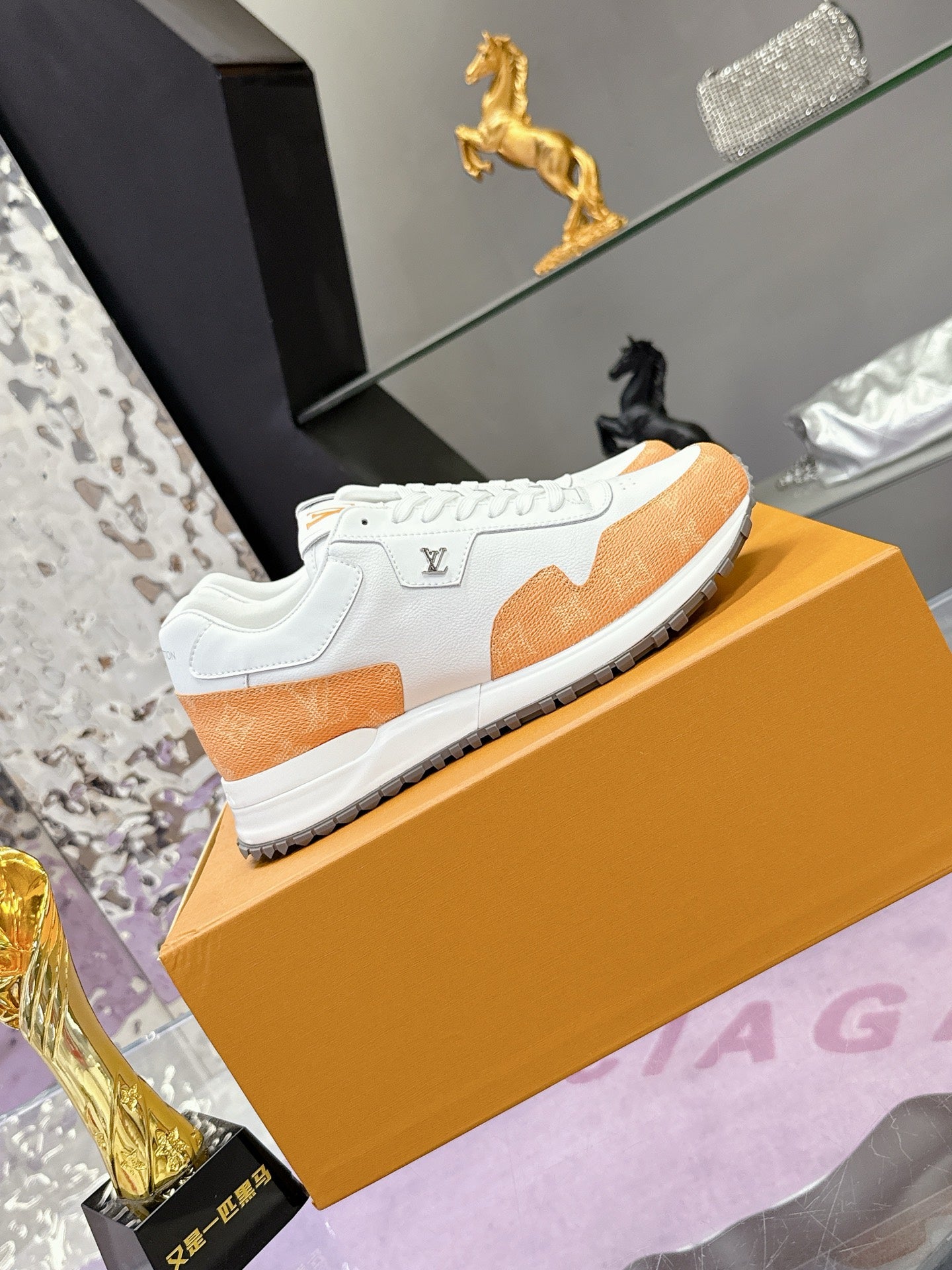 White low-top sneakers with orange accent panels, lace-up closure, and textured sole