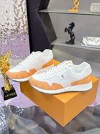 Two white lace-up sneakers with orange side panels and small logo on the side