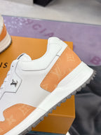 White leather sneaker with orange textured panel, side logo, and lace-up detail