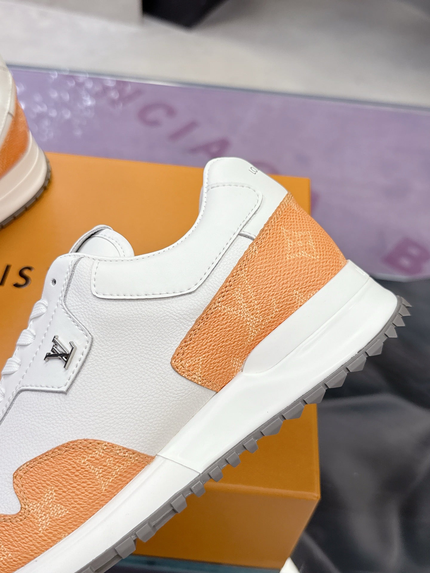 White leather sneaker with orange textured panel, side logo, and lace-up detail