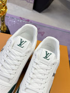 Close-up of white sneakers showing green LV logo on tongue