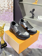 Louis Vuitton sneakers pair on box, dark and silver monogram-style panels, lace-up.