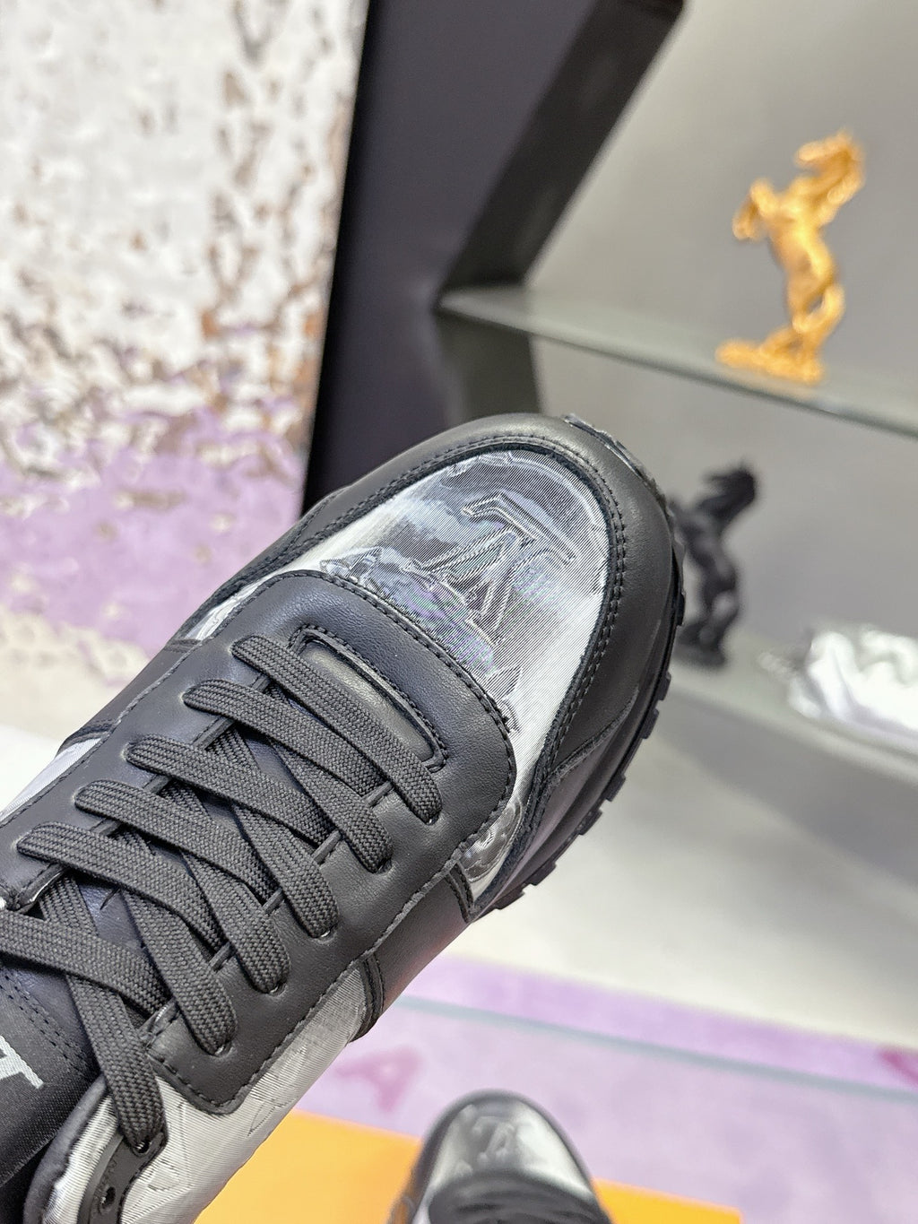 Louis Vuitton sneaker toe detail, dark laces over silver-toned monogram panel.