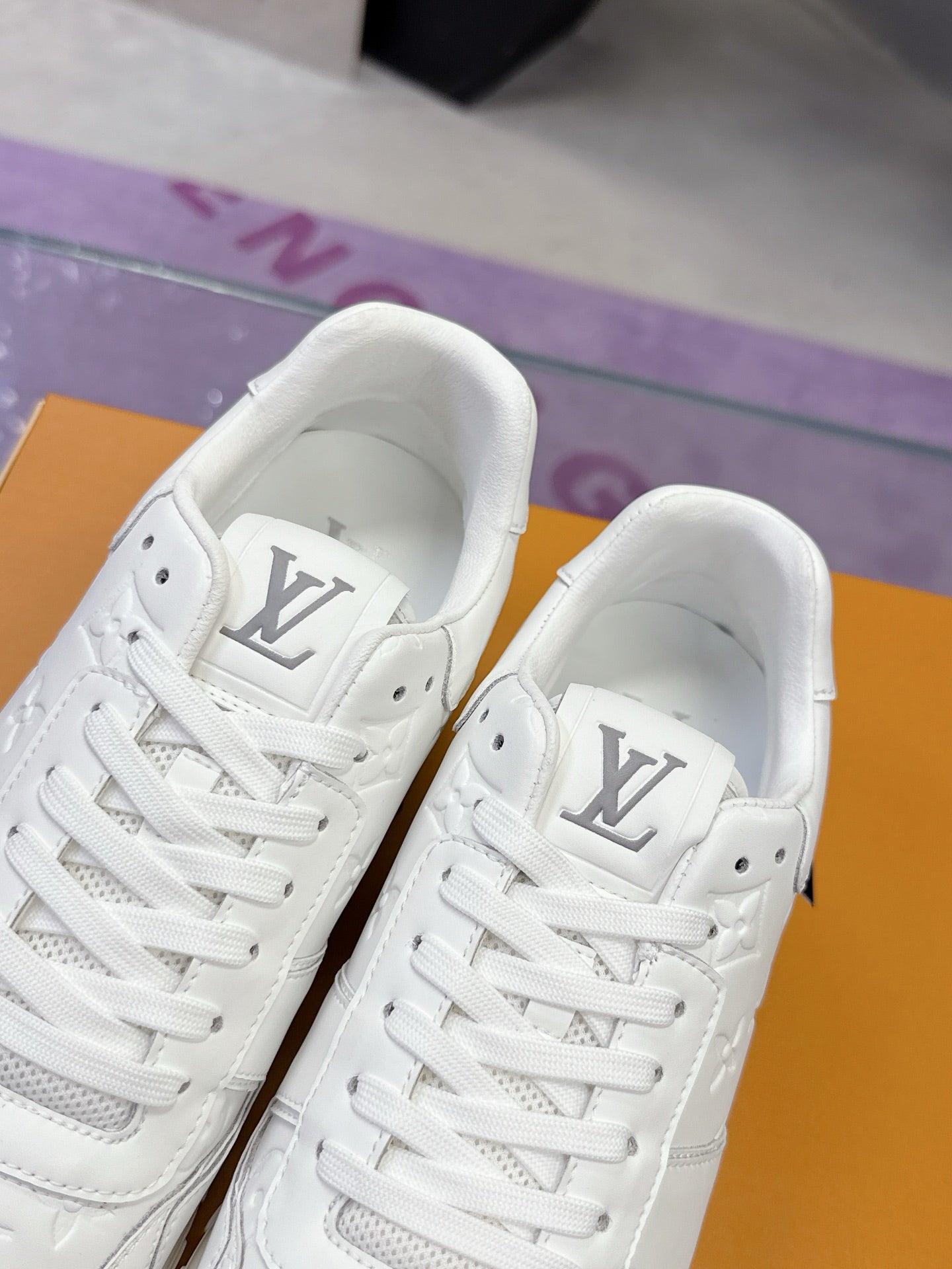 White women's sneakers close-up showing lace-up front and embossed logo on quarter