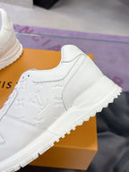 White women's sneaker side view with embossed monogram texture and chunky sole