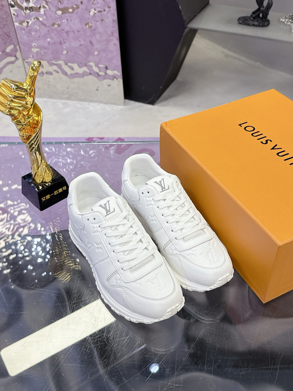White women's lace-up sneakers on a box, with embossed monogram and thick outsole