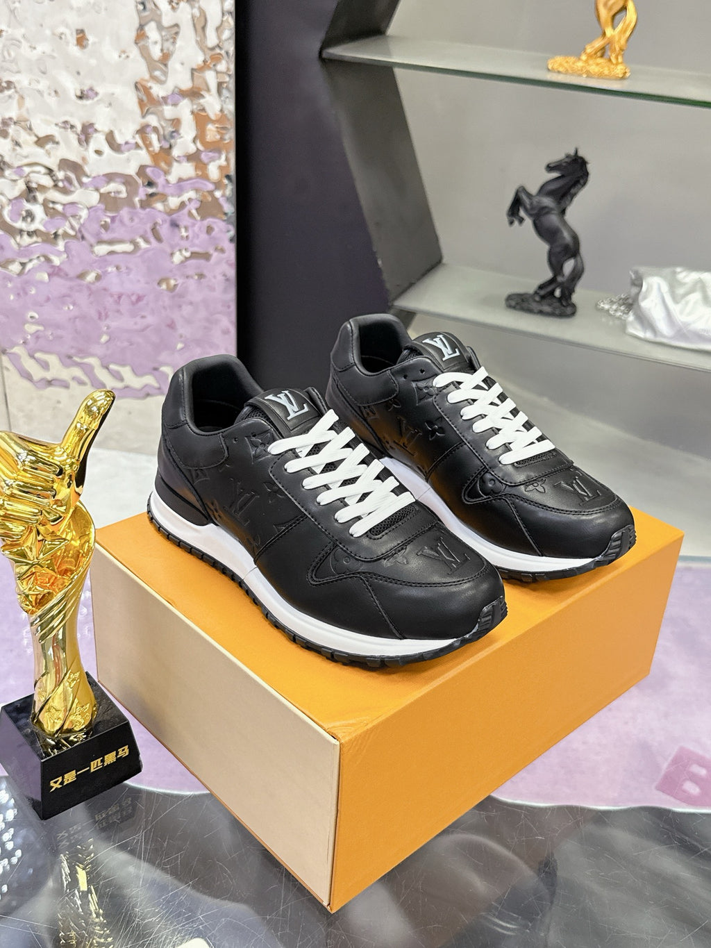 Louis Vuitton black leather sneakers on display box, white lace-up front