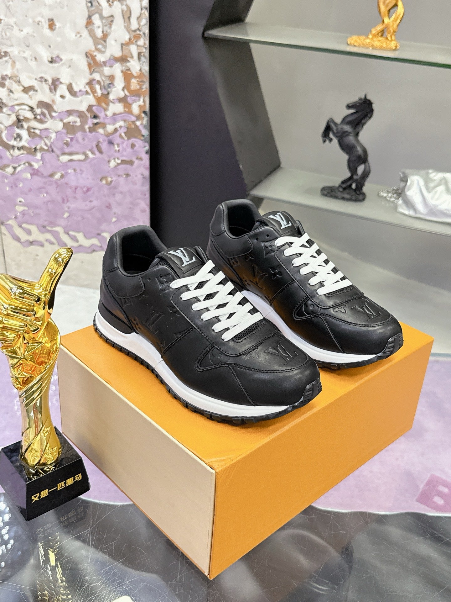 Louis Vuitton black leather sneakers on display box, white lace-up front