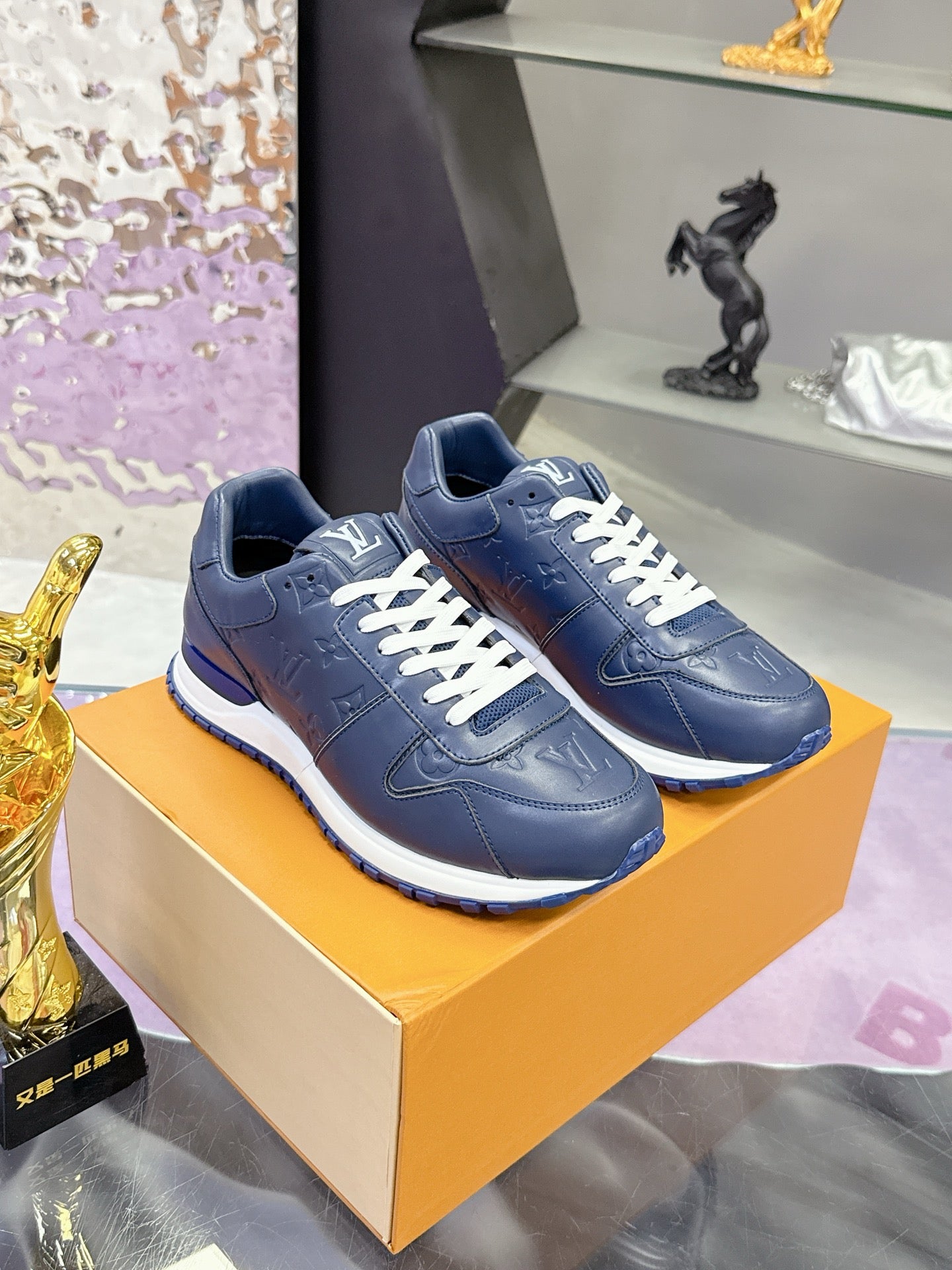 Blue leather low-top sneakers on orange box, white laces and striped sole.