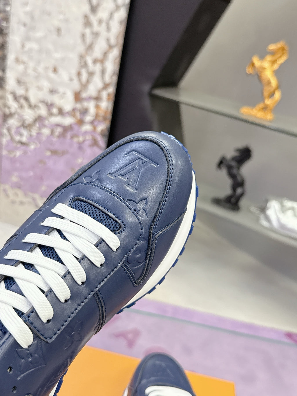 Blue leather low-top sneaker close-up, white laces, embossed logo on toe cap.