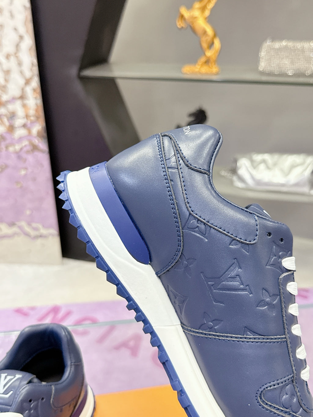 Blue leather low-top sneaker close-up, white laces, sculpted sole and side stitching.