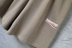 Balenciaga logo patch on hem of taupe cotton shorts, side view