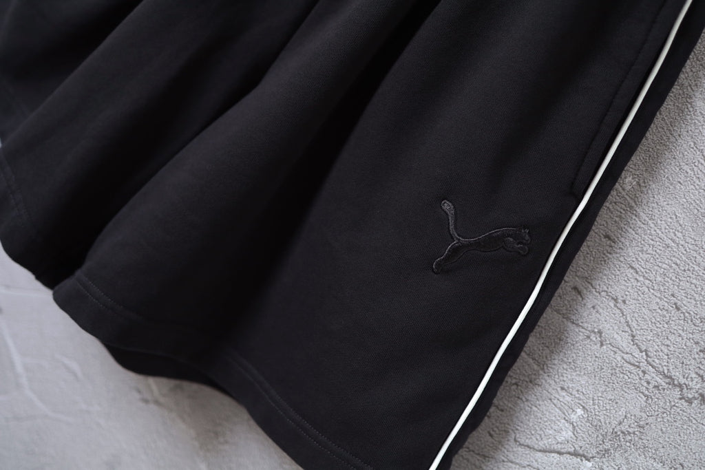 Close-up of black shorts hem with side stripe and Puma logo