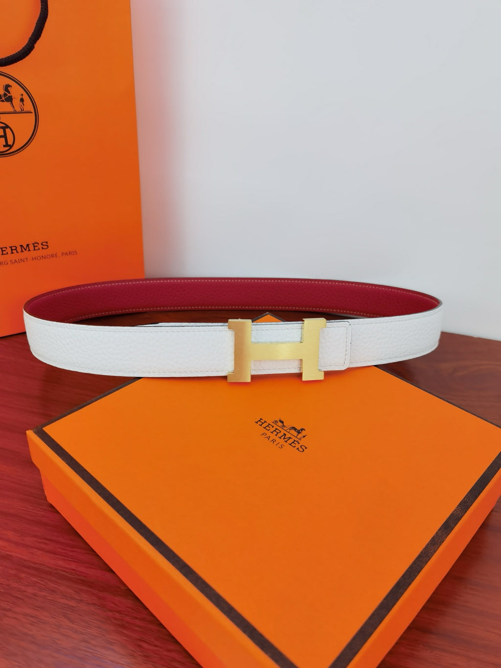 White leather belt with gold-toned square buckle; red reversible side visible