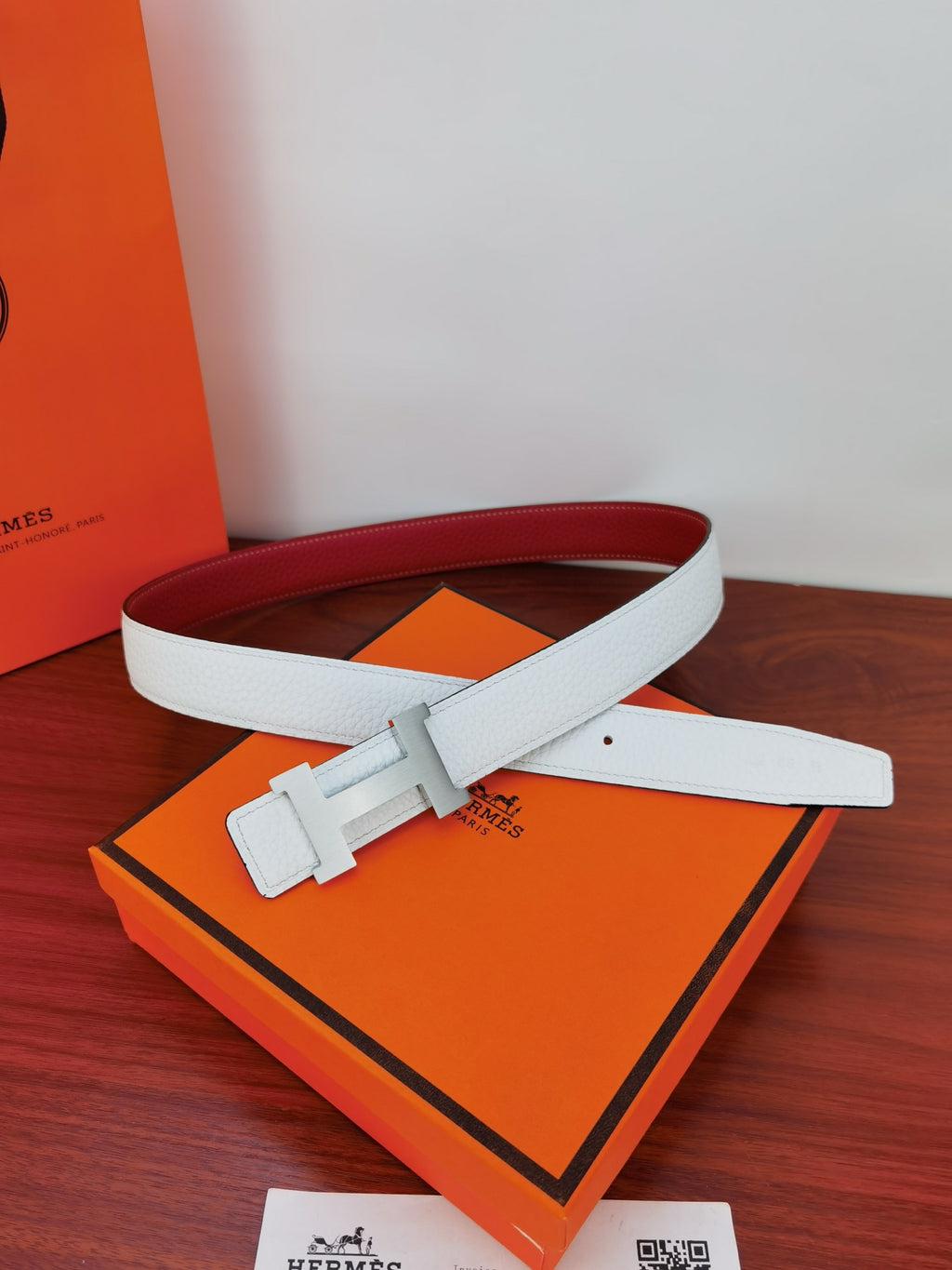 Reversible leather belt with red inner side and white outer; square buckle