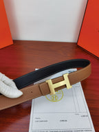 Reversible leather belt, tan front and dark back with gold H buckle, receipt beside