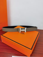 Hermes belt on orange box, light gray strap with gold-tone H buckle