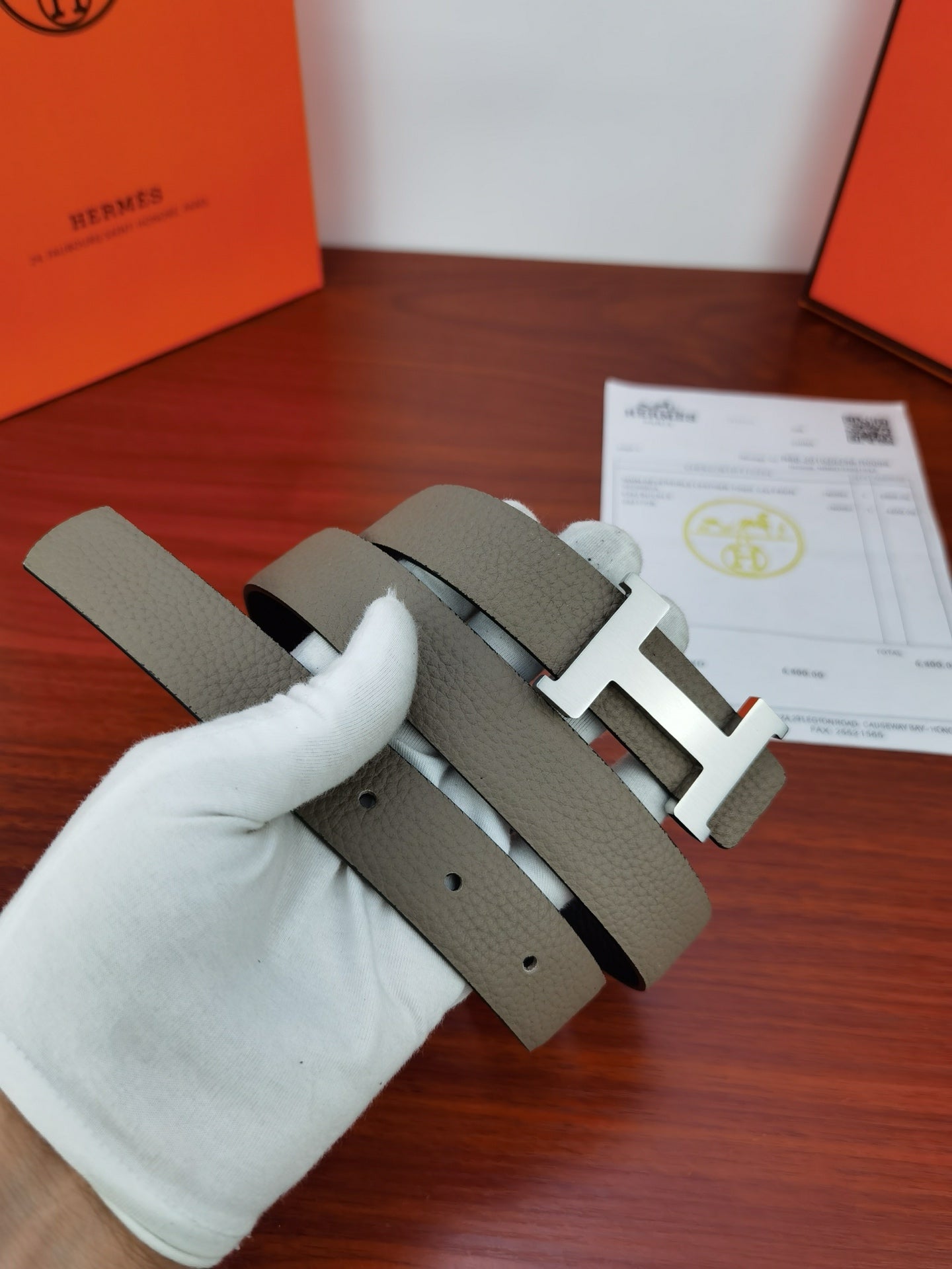 Hermes belt with light gray strap and gold-tone H buckle, pair shown