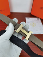 Hermes belt with light gray strap and gold-tone H buckle, shown folded