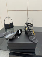 Black heeled sandals and matching black handbag with gold YSL logo