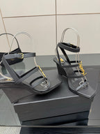 Black heeled sandals with gold chain detail, open toe and crisscross straps