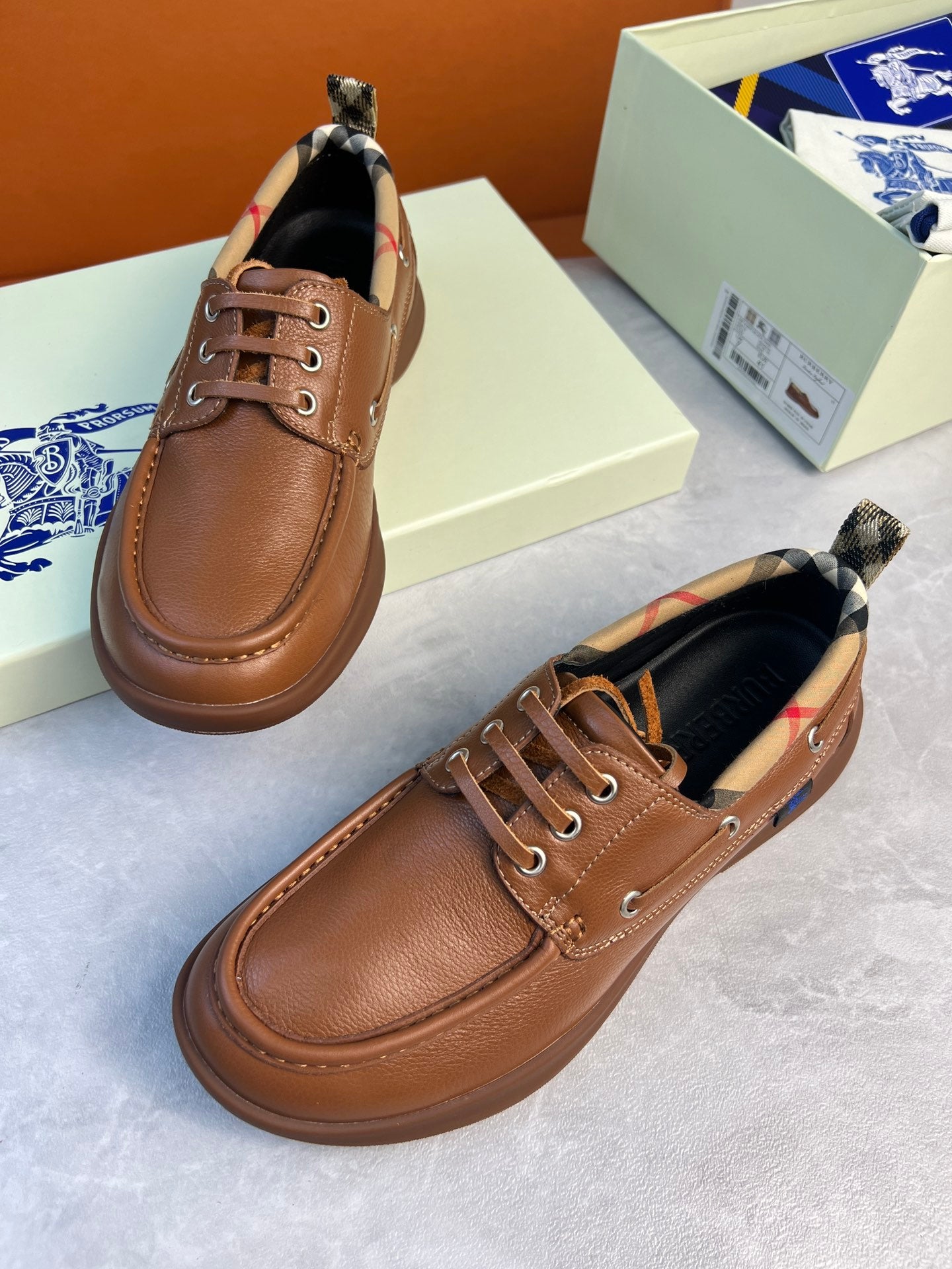 Burberry brown leather lace-up boat shoes angled view with checkered lining and lace-up front